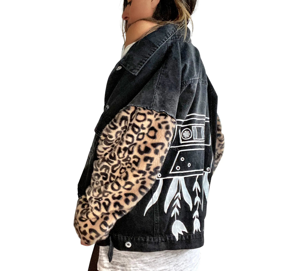 Black denim jacket with super comfortable leopard pattern sleeves. Large white cassette tape painted on back, with white flowers and leaves sprouting out. Signed @wrenandglory.