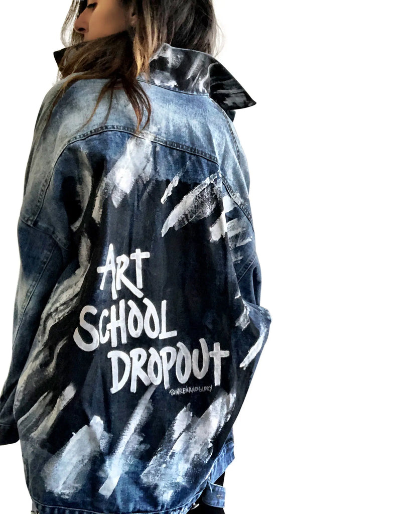 Dark blue denim jacket with long back. White and black pattern painted on back, with ART SCHOOL DROPOUT painted over it in white. Collar and front pockets painted with black and white pattern. Signed @wrenandglory.