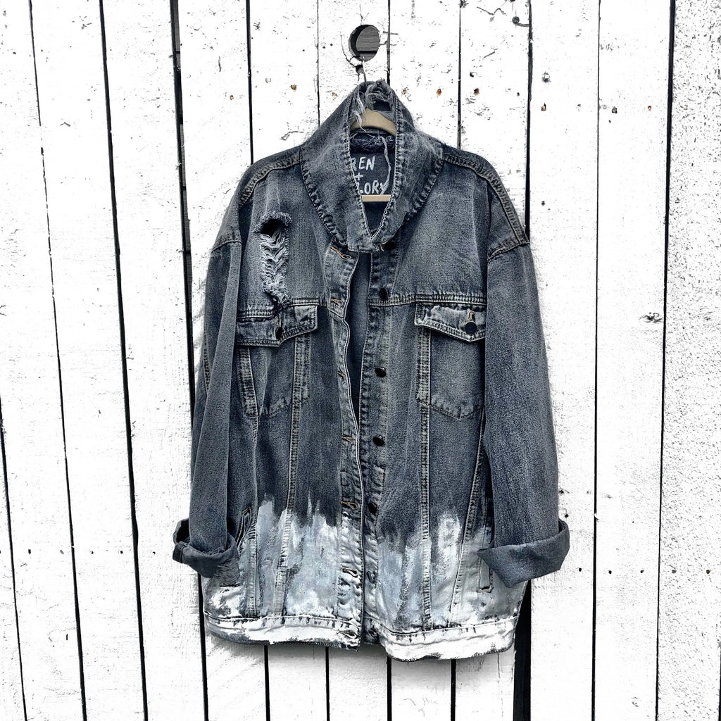 Faded black denim. FREE BIRD painted in white in block letters on back, with a silhouette on a bird in black over it. Signed @wrenandglory.