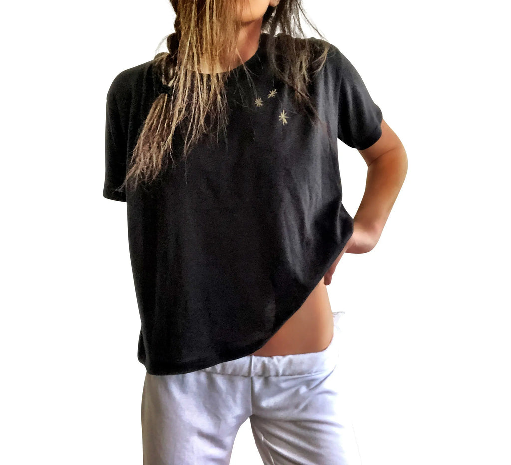 The perfect cropped black T shirt. Assorted color metallics and white splatter and stripes painted on back, with small stars painted on front, upper left side in gold. Signed @wrenandglory.