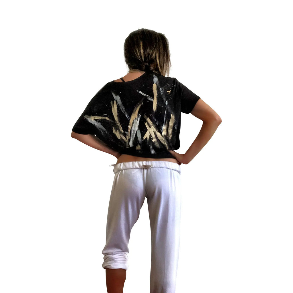 The perfect cropped black T shirt. Assorted color metallics and white splatter and stripes painted on back, with small stars painted on front, upper left side in gold. Signed @wrenandglory.