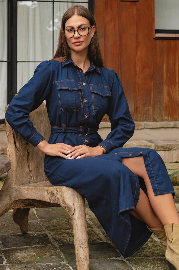 Woman wearing a blue denim dress sitting on a wooden bench outdoors- cottage core style