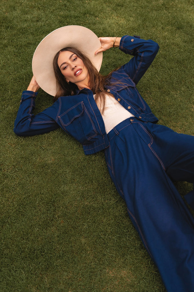Woman in a blue outfit and beige hat lying on grass - cottage core style