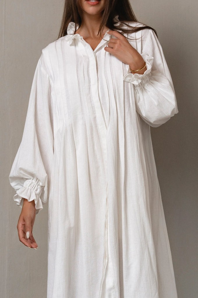 White long-sleeve dress worn by a person on a plain background
